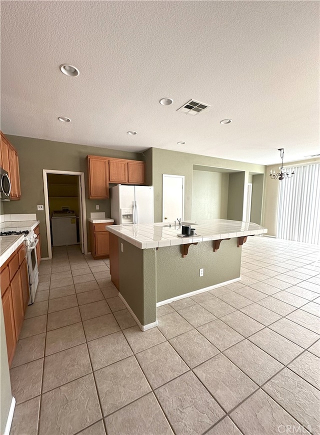 1256 Sunburst Dr, Beaumont, CA 92223 - kitchen featuring white appliances, light tile patterned floors, tile counters, a textured ceiling, and brown cabinets