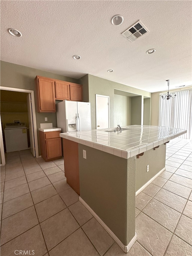 1256 Sunburst Dr, Beaumont, CA 92223 - kitchen with white fridge with ice dispenser, tile countertops, a textured ceiling, a spacious island, and light tile patterned floors