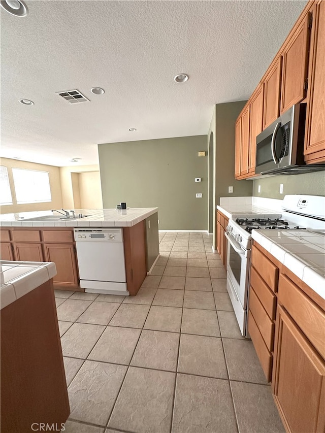 1256 Sunburst Dr, Beaumont, CA 92223 - kitchen featuring white appliances, tile countertops, light tile patterned floors, a textured ceiling, and recessed lighting