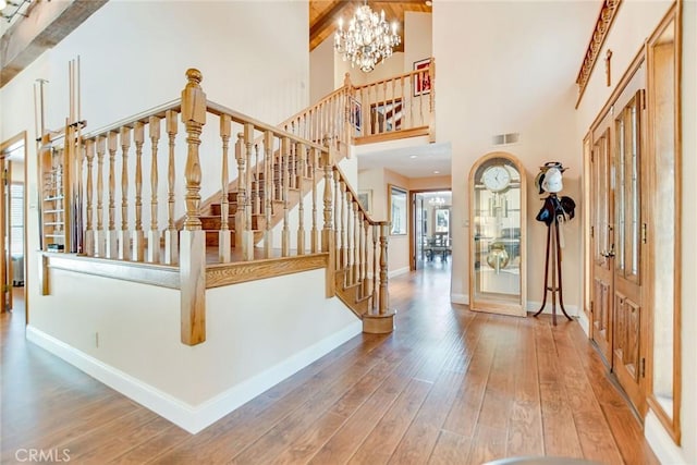 1013 Idaho Ct, Claremont, CA 91711 - entryway featuring wood-type flooring, stairs, a towering ceiling, beam ceiling, and a chandelier