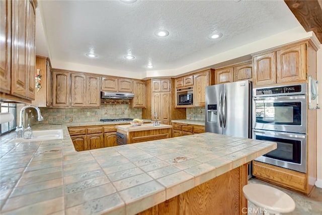 1013 Idaho Ct, Claremont, CA 91711 - kitchen featuring appliances with stainless steel finishes, tile counters, under cabinet range hood, decorative backsplash, and a textured ceiling