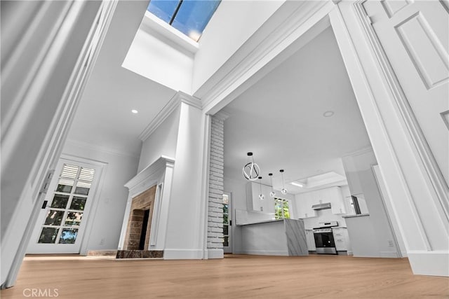 2610 Via Pacheco, Palos Verdes Estates, CA 90274 - unfurnished living room featuring a fireplace with raised hearth, ornamental molding, a skylight, and light wood-style flooring
