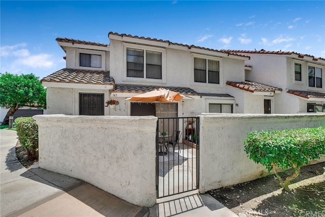9765 Alburtis Ave Unit 143, Santa Fe Springs, CA 90670 - view of front of property with a fenced front yard, a tile roof, a gate, and stucco siding