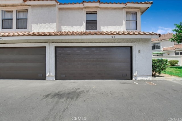 9765 Alburtis Ave Unit 143, Santa Fe Springs, CA 90670 - view of property with an attached garage, a tiled roof, and stucco siding