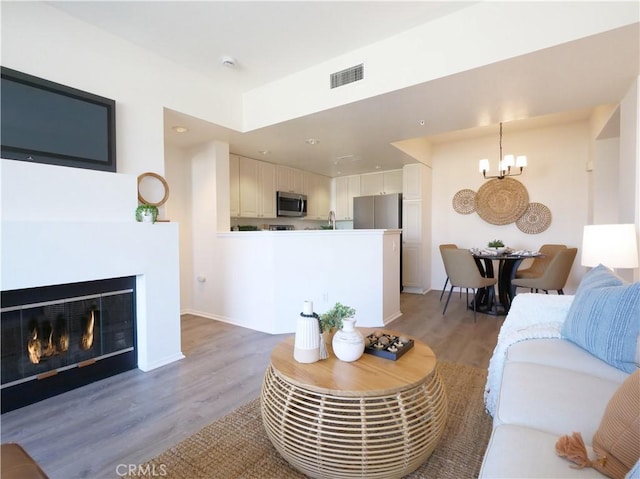 1281 Cabrillo Ave Unit 303, Torrance, CA 90501 - living area with light wood-style floors, a chandelier, a glass covered fireplace, and recessed lighting