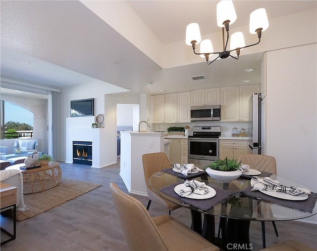 1281 Cabrillo Ave Unit 303, Torrance, CA 90501 - dining space featuring a chandelier, wood finished floors, a glass covered fireplace, and recessed lighting