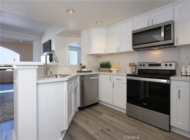 1281 Cabrillo Ave Unit 306, Torrance, CA 90501 - kitchen with appliances with stainless steel finishes, white cabinets, light wood finished floors, a peninsula, and light countertops
