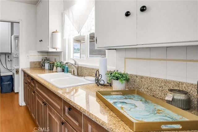 74697 Baseline Rd Unit 29, Palms, CA 92277 - kitchen featuring decorative backsplash, brown cabinetry, light wood-style flooring, and light stone countertops