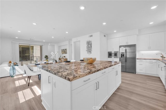 208 Harringay, Irvine, CA 92618 - kitchen with stainless steel appliances, light stone countertops, light wood-type flooring, a kitchen island, and white cabinetry