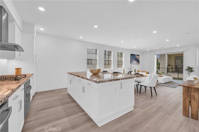 208 Harringay, Irvine, CA 92618 - kitchen featuring wall chimney exhaust hood, light wood-type flooring, dark stone countertops, stainless steel appliances, and white cabinets