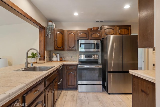 406 University Ave, Burbank, CA 91504 - kitchen featuring stainless steel appliances, tile counters, backsplash, recessed lighting, and dark brown cabinets