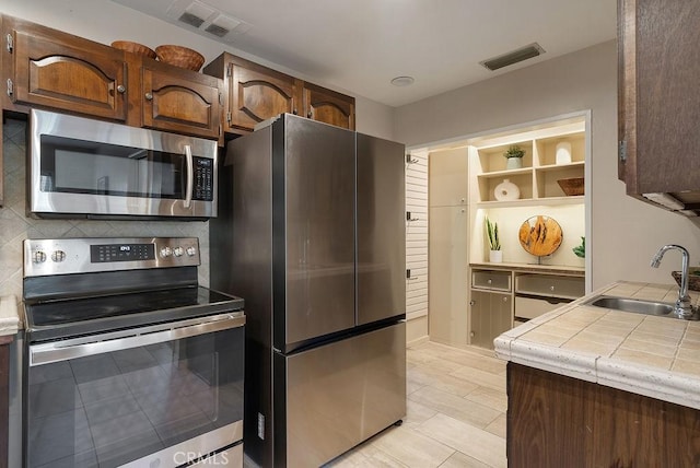 406 University Ave, Burbank, CA 91504 - kitchen featuring stainless steel appliances, tile counters, decorative backsplash, open shelves, and light tile patterned floors