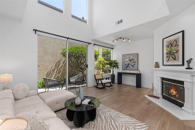 54 Hawaii Dr, Aliso Viejo, CA 92656 - living area featuring a glass covered fireplace, wood finished floors, and a towering ceiling