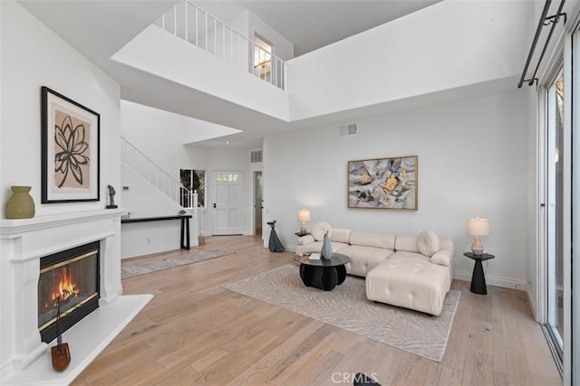 54 Hawaii Dr, Aliso Viejo, CA 92656 - living room with wood finished floors, stairs, a glass covered fireplace, and a high ceiling