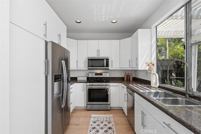 54 Hawaii Dr, Aliso Viejo, CA 92656 - kitchen with appliances with stainless steel finishes, dark countertops, white cabinetry, light wood-type flooring, and recessed lighting
