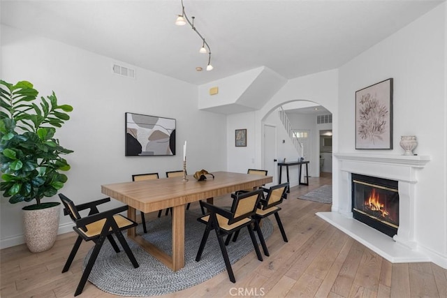 54 Hawaii Dr, Aliso Viejo, CA 92656 - dining space with arched walkways, light wood-style floors, and a glass covered fireplace
