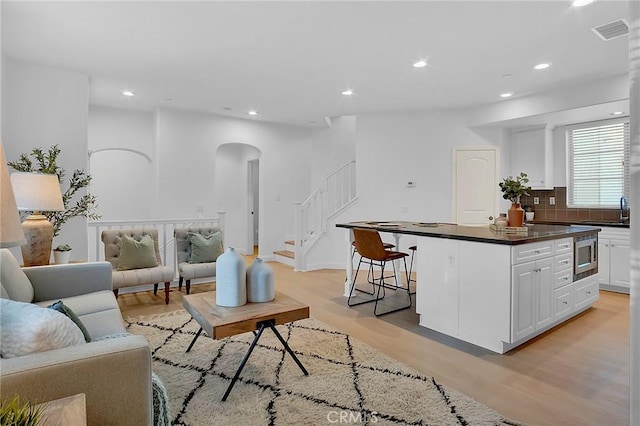 1749 Grand Ave Unit 4, Long Beach, CA 90804 - living room with light wood-style flooring, stairway, arched walkways, and recessed lighting