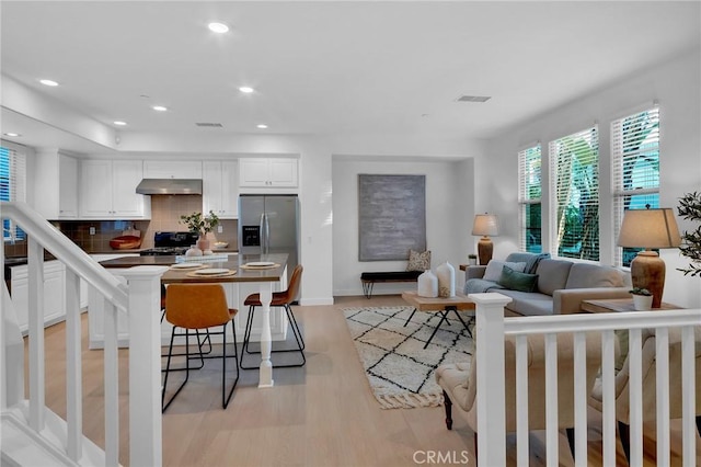 1749 Grand Ave Unit 4, Long Beach, CA 90804 - kitchen with stainless steel fridge with ice dispenser, under cabinet range hood, white cabinets, tasteful backsplash, and light wood-type flooring