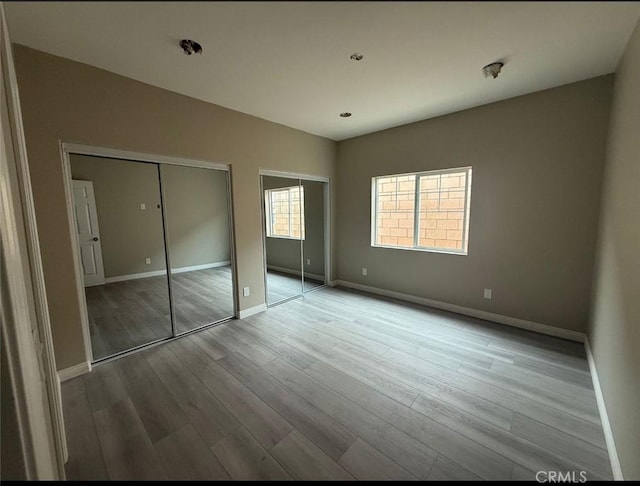 7398 N Maple Ave, Fontana, CA 92336 - unfurnished bedroom featuring two closets and wood finished floors