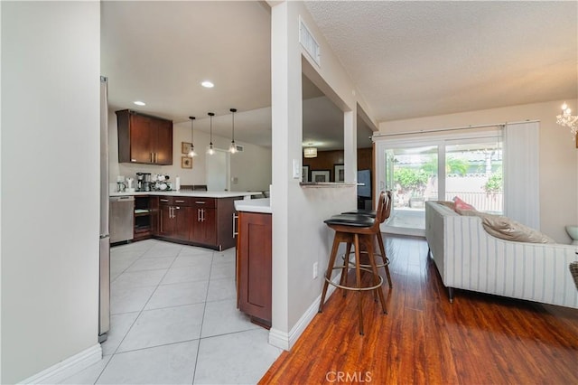 1068 Richmond Dr, Claremont, CA 91711 - kitchen featuring light countertops, a peninsula, a breakfast bar area, a chandelier, and decorative light fixtures