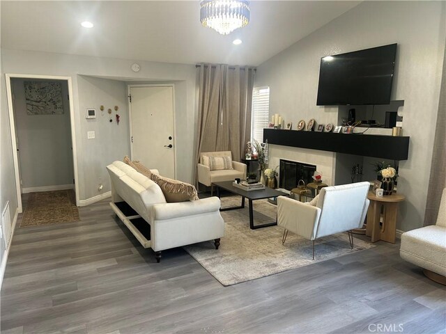 2258 El Rio St, Lancaster, CA 93535 - living room featuring wood finished floors, recessed lighting, lofted ceiling, a glass covered fireplace, and a chandelier