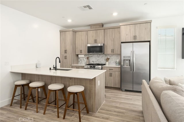 480 W Balsam Ln, Clovis, CA 93611 - kitchen featuring appliances with stainless steel finishes, a breakfast bar area, tasteful backsplash, light wood finished floors, and recessed lighting