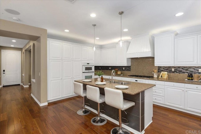 15809 Concord Rdg, San Diego, CA 92127 - kitchen with custom exhaust hood, stainless steel gas stovetop, tasteful backsplash, stone counters, and white cabinetry