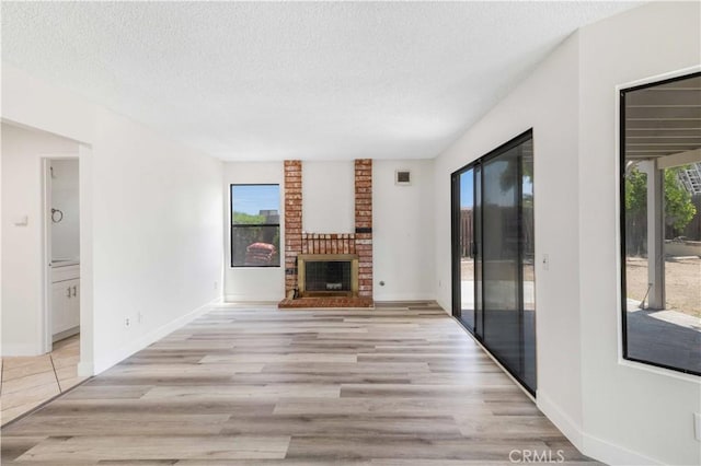 14225 Woodpark Dr, Moreno Valley, CA 92553 - unfurnished living room with light wood finished floors, a textured ceiling, and a brick fireplace