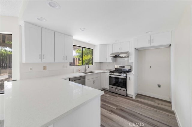 14225 Woodpark Dr, Moreno Valley, CA 92553 - kitchen featuring stainless steel appliances, under cabinet range hood, a peninsula, white cabinetry, and light wood finished floors