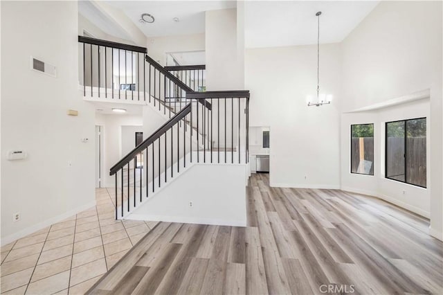 14225 Woodpark Dr, Moreno Valley, CA 92553 - unfurnished living room with high vaulted ceiling, a chandelier, wood finished floors, and stairway
