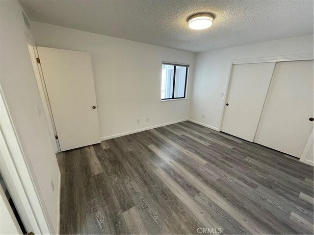1935 W Santa Ana Ave, Fresno, CA 93705 - unfurnished bedroom featuring a textured ceiling, dark wood-style flooring, and a closet