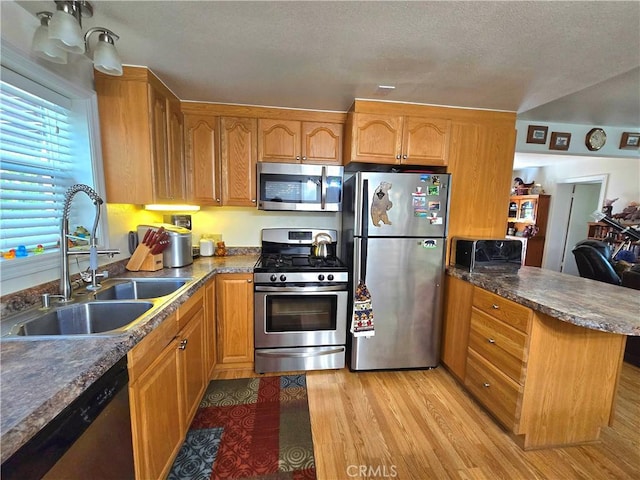 2445 Spring Dr, Running Springs, CA 92382 - kitchen featuring appliances with stainless steel finishes, a peninsula, light wood finished floors, brown cabinetry, and a textured ceiling