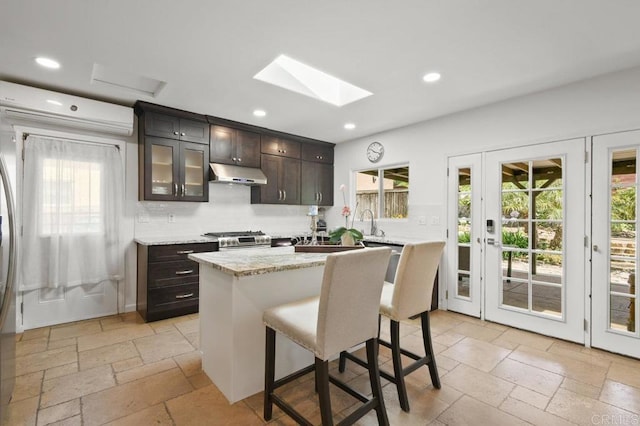 6038 Bradford St, San Diego, CA 92115 - kitchen featuring under cabinet range hood, stone tile flooring, stainless steel range, a skylight, and recessed lighting