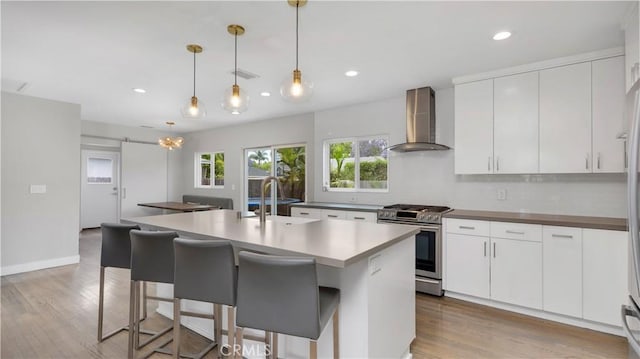5202 E Conant St, Long Beach, CA 90808 - kitchen featuring wall chimney exhaust hood, gas stove, light wood-style floors, recessed lighting, and a breakfast bar area
