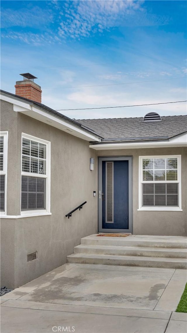 5202 E Conant St, Long Beach, CA 90808 - doorway to property featuring roof with shingles, a chimney, stucco siding, and a patio