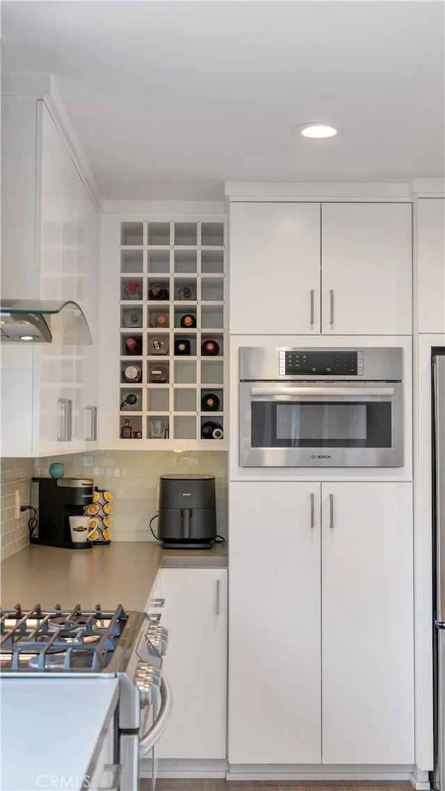 5202 E Conant St, Long Beach, CA 90808 - kitchen with appliances with stainless steel finishes, white cabinets, decorative backsplash, and light countertops