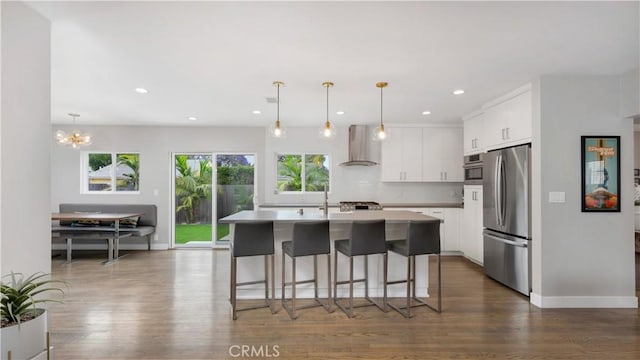 5202 E Conant St, Long Beach, CA 90808 - kitchen featuring freestanding refrigerator, wall chimney exhaust hood, dark wood-type flooring, a breakfast bar, and white cabinetry