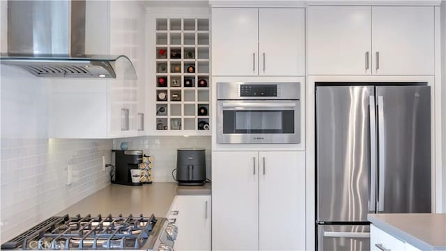 5202 E Conant St, Long Beach, CA 90808 - kitchen featuring appliances with stainless steel finishes, wall chimney range hood, decorative backsplash, white cabinetry, and light countertops