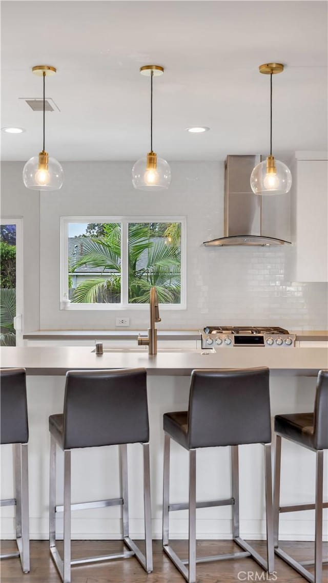 5202 E Conant St, Long Beach, CA 90808 - kitchen with wall chimney range hood, decorative backsplash, a breakfast bar area, and hanging light fixtures
