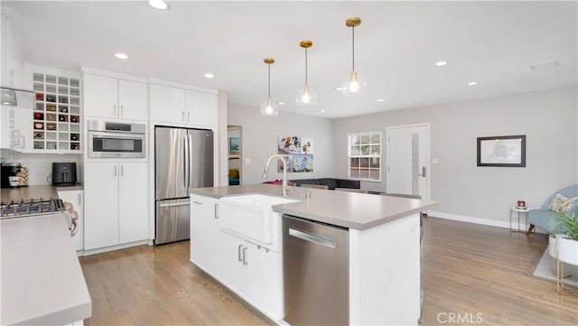 5202 E Conant St, Long Beach, CA 90808 - kitchen with appliances with stainless steel finishes, light wood-style flooring, white cabinetry, an island with sink, and light countertops