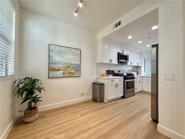 13390 Savanna, Tustin, CA 92782 - kitchen with stainless steel appliances, light wood-type flooring, light countertops, white cabinetry, and tasteful backsplash