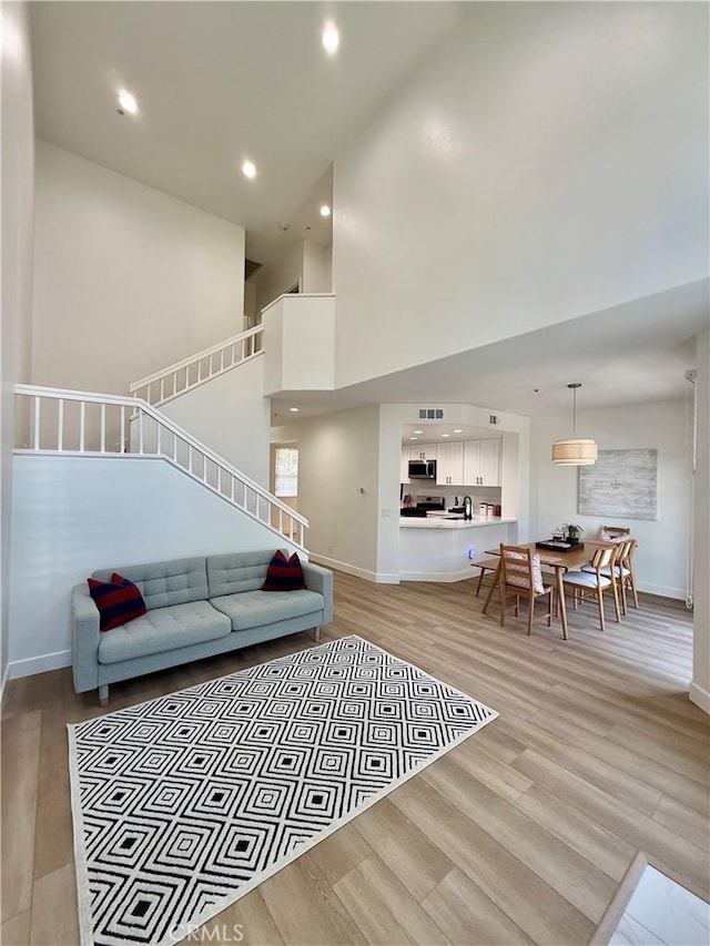 13390 Savanna, Tustin, CA 92782 - living room with light wood finished floors, stairway, recessed lighting, and a towering ceiling