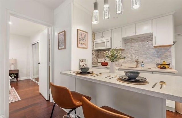 225 W 6th St Unit 206, Long Beach, CA 90802 - kitchen with white appliances, a kitchen breakfast bar, backsplash, white cabinetry, and dark wood-style floors
