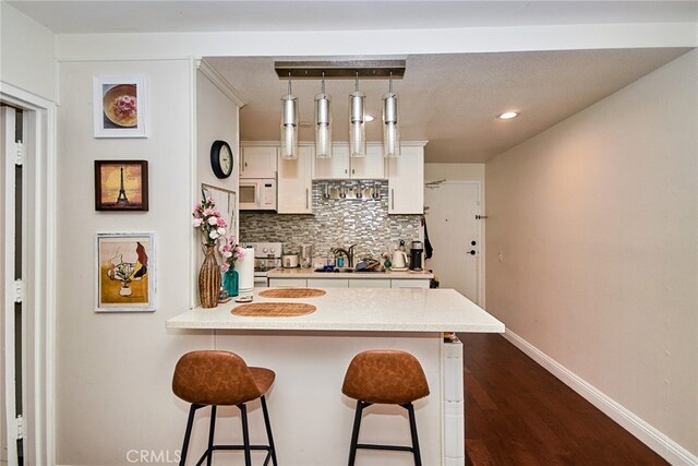 225 W 6th St Unit 206, Long Beach, CA 90802 - kitchen featuring a kitchen breakfast bar, white appliances, tasteful backsplash, a peninsula, and white cabinets