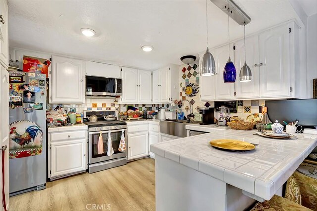12161 Napoli Dr, Cerritos, CA 90703 - kitchen featuring stainless steel appliances, tile counters, white cabinets, a peninsula, and recessed lighting
