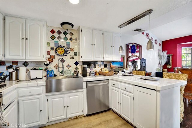 12161 Napoli Dr, Cerritos, CA 90703 - kitchen with stainless steel dishwasher, a peninsula, white cabinetry, and decorative backsplash