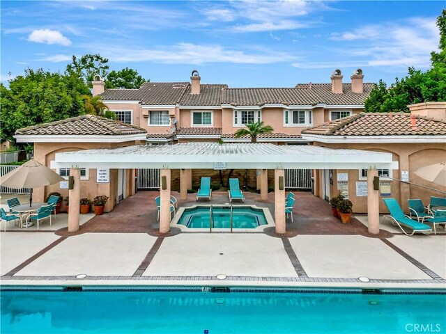 12161 Napoli Dr, Cerritos, CA 90703 - rear view of property with a hot tub, a patio area, stucco siding, and a community pool