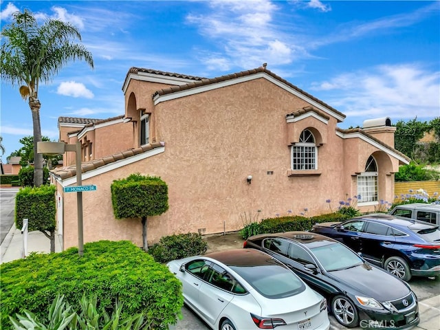 12161 Napoli Dr, Cerritos, CA 90703 - view of side of property with uncovered parking, stucco siding, and a tiled roof