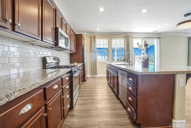 29234 St Andrews, Lake Elsinore, CA 92530 - kitchen featuring stainless steel appliances, ornamental molding, a center island with sink, backsplash, and light stone countertops