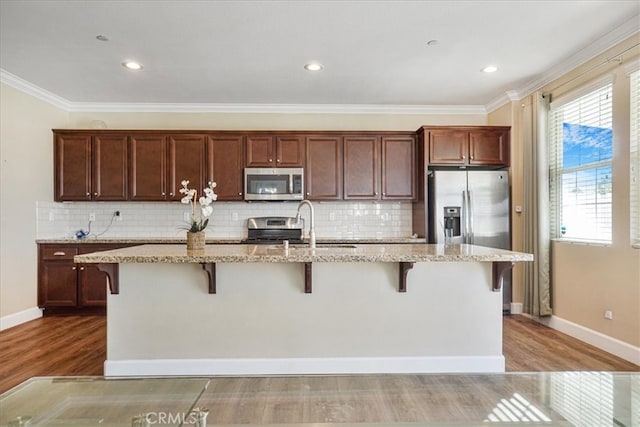 29234 St Andrews, Lake Elsinore, CA 92530 - kitchen featuring appliances with stainless steel finishes, wood finished floors, a breakfast bar, crown molding, and light stone counters